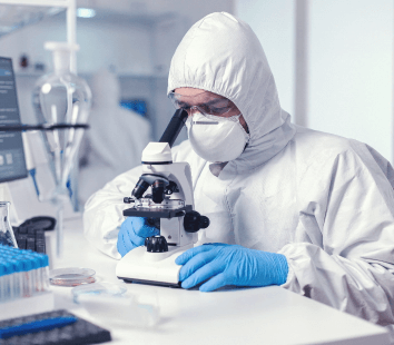 microbiologist-with-protection-glasses-using-microscope-dressed-ppe-suit